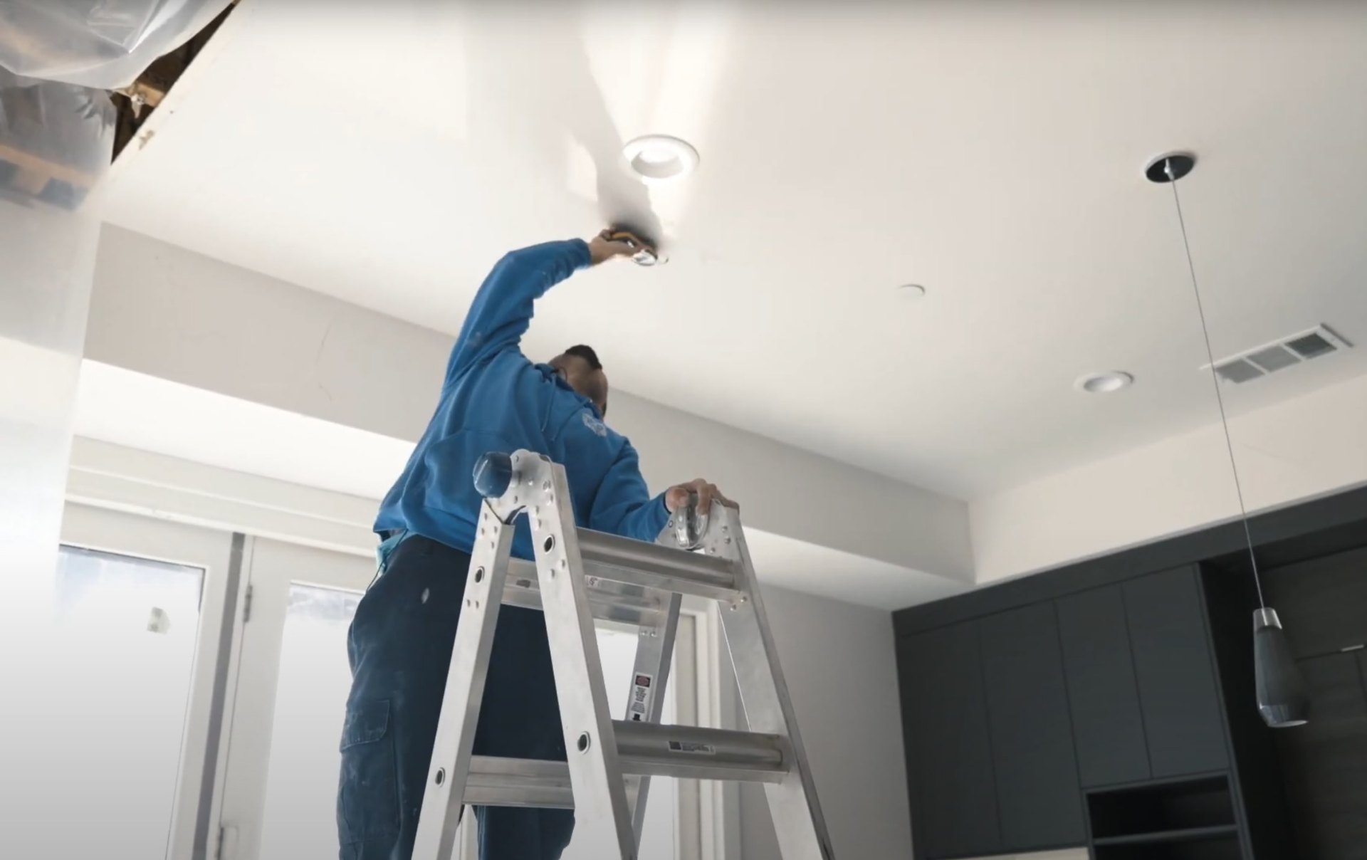 Professional water damage restoration technician inspecting ceiling damage with specialized equipment
