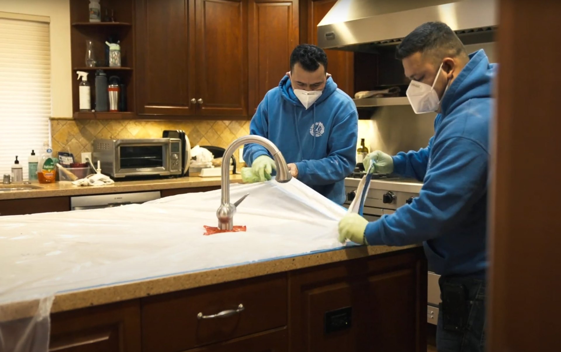 Water damage restoration team working in kitchen with professional equipment and protective gear