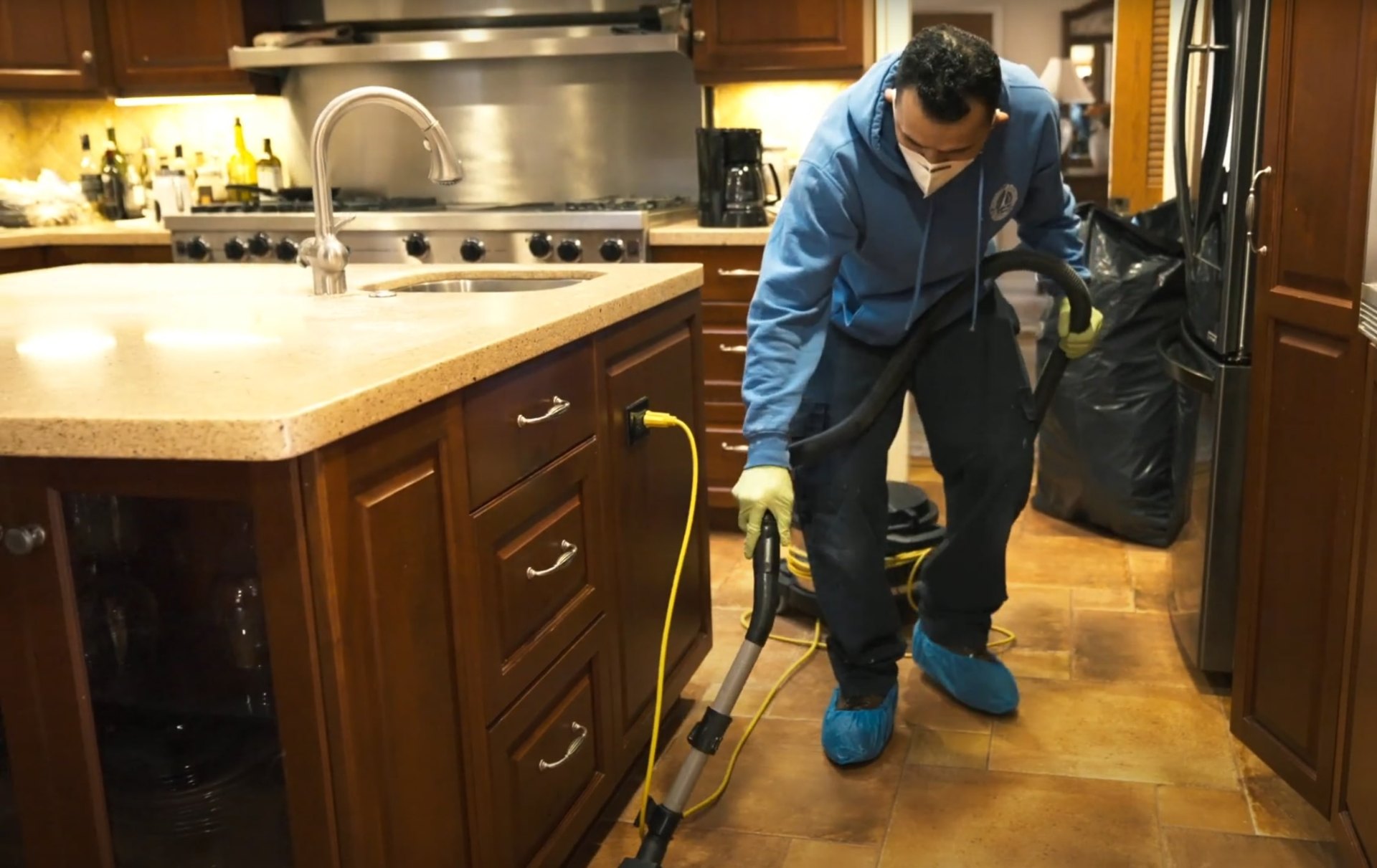 Water damage restoration specialist cleaning and sanitizing kitchen surfaces with professional equipment